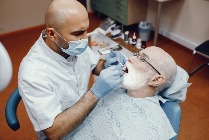 Dentist checks older patient’s mouth