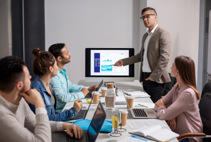 Manager with a computer screen and talking to colleagues